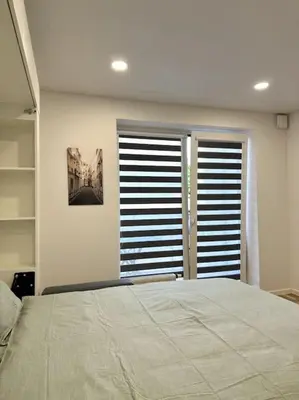 a bedroom with a large bed and two windows at Wolfie Apartment, City Center in Vilnius