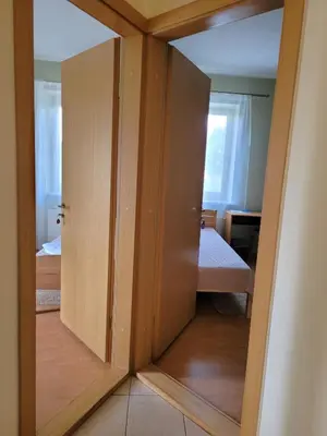 a room with a cupboard and a bedroom with a bed at Jono Pauliaus II piligrimu namai in Raseiniai