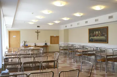a room with tables and chairs and a cross on the wall at Jono Pauliaus II piligrimu namai in Raseiniai