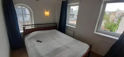 a small bed in a room with two windows at Loft style apartments in Kaunas center in Kaunas