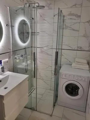 a bathroom with a washing machine and a glass shower at Vanilės home in Šiauliai