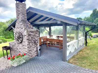 a pavilion with a wooden table in a garden at GREY PINE HOUSE in Druskininkai