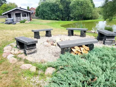 two picnic tables and logs in a park at GREY PINE HOUSE in Druskininkai