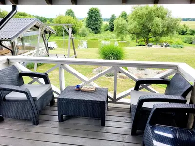 a porch with chairs and a table and a view of a park at GREY PINE HOUSE in Druskininkai