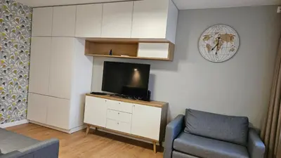 a living room with a tv and a chair at Modern Studio Apartment in Marijampolė