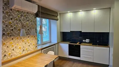 a kitchen with white cabinets and a table and a window at Modern Studio Apartment in Marijampolė
