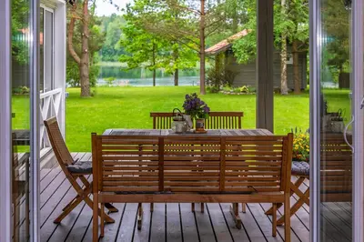 a table and chairs on a porch with a view of a yard at Vila Shakti in Rudžionys