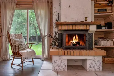 a fireplace in a living room with a chair at Vila Shakti in Rudžionys