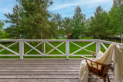 a rocking chair on a porch with a white fence at Vila Shakti in Rudžionys