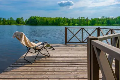 a chair sitting on a dock next to a lake at Vila Shakti in Rudžionys
