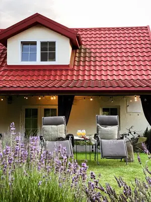 a group of chairs sitting on a yard with a red roof at Mėta House in Merkinė