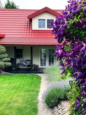 a house with a red roof and purple flowers at Mėta House in Merkinė