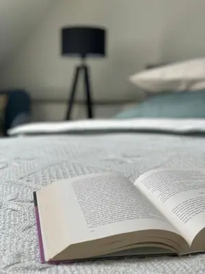 an open book sitting on top of a bed at Mėta House in Merkinė