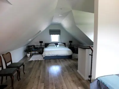 a attic bedroom with a bed and a window at Mėta House in Merkinė