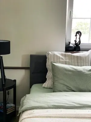a bedroom with a bed with two pillows and a lamp at Mėta House in Merkinė