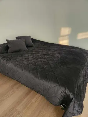 a large black bed sitting on a wooden floor at Prie Vilneles Apartment in Vilnius