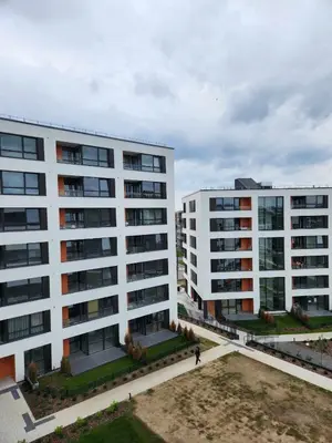 two white buildings with people walking in front of them at Prie Vilneles Apartment in Vilnius