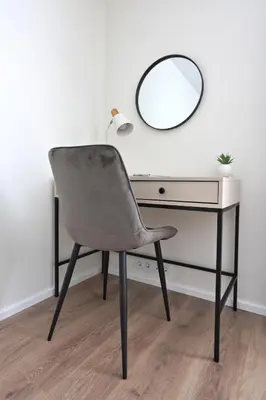a chair in front of a desk with a mirror at Aušros apartamentai in Utena