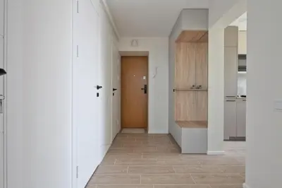a hallway with white walls and a wooden door at Aušros apartamentai in Utena