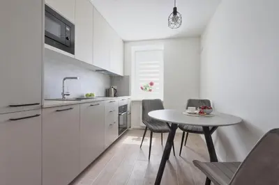 a white kitchen with a small table and chairs at Aušros apartamentai in Utena