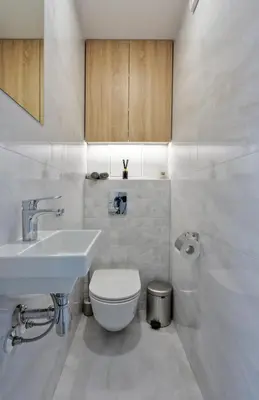 a white bathroom with a toilet and a sink at Aušros apartamentai in Utena