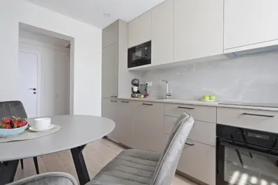 a kitchen with white cabinets and a table and chairs at Aušros apartamentai in Utena