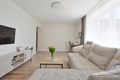 a white living room with a couch and a table at Aušros apartamentai in Utena