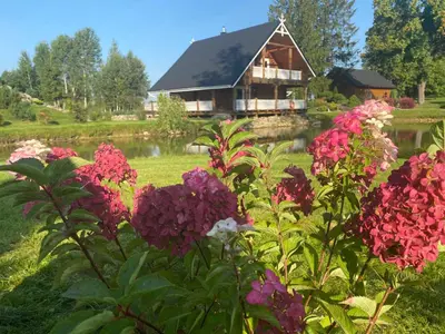a house and flowers in front of a lake at Pas sesutes sodyba in Pamarnakai