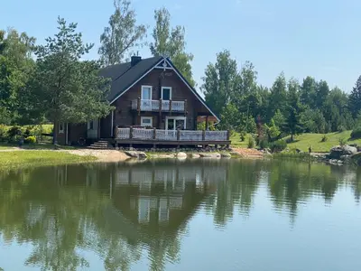 a house sitting on the shore of a lake at Pas sesutes sodyba in Pamarnakai