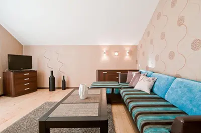 a living room with a blue couch and a tv at Abariaus Apartamentai in Druskininkai