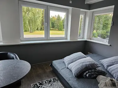 a bedroom with two beds and two windows at Park apartments in Rokiškis