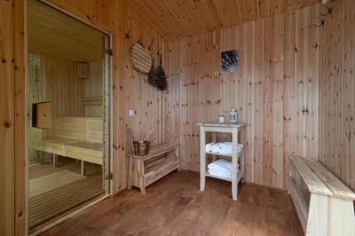 a wooden room with a sauna with a table and a bench at Villa Green in Molėtai