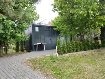a black building with a table next to a sidewalk at Šaltupio kaimo turizmas in Pakumprys