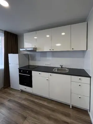 a kitchen with white cabinets and a black counter top at Stiklo Apartamentai in Radviliškis