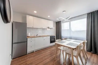 a kitchen with white cabinets and a table and chairs at Stiklo Apartamentai in Radviliškis