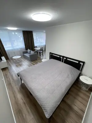a bedroom with a large bed and a living room at Stiklo Apartamentai in Radviliškis