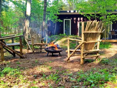 two chairs sitting around a fire in front of a house at Miško sielos namelis su pirtele in Aukštelkė