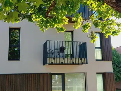 a building with a balcony with a chair on it at Birštono Perlas apartamentai in Birštonas