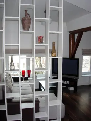 a white book shelf in a living room with a tv at Studio in Kaunas City in Kaunas