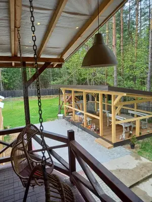 a porch with a swing and a house at My Forest Villa in Vilnius