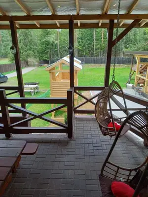 a porch with a swing and a bird house at My Forest Villa in Vilnius