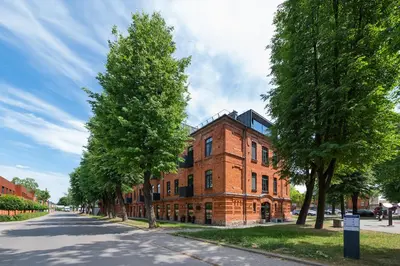 a brick building with trees in front of a street at Spaciuos 1 BD Apt by Domvia in Kaunas
