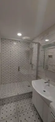 a white bathroom with a shower and a sink at Trumpalaikė apartamentų nuoma centre (Vytauto g.) in Šiauliai