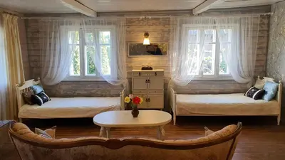 a room with two beds and a table and two windows at Authentic homestead over 100 years old in Kėdainiai