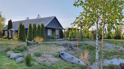 a house with a garden and a boat in front of it at Authentic homestead over 100 years old in Kėdainiai