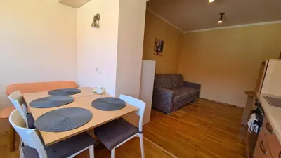 a dining room with a table and chairs and a couch at Apartamentai Luna in Druskininkai