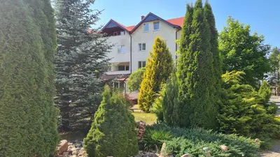 a garden in front of a building with trees at Apartamentai Luna in Druskininkai