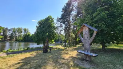 a statue of a person on a bench next to a lake at Apartamentai Luna in Druskininkai