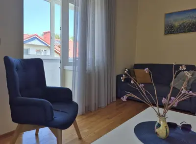 a living room with a blue chair and a couch at Apartamentai Luna in Druskininkai