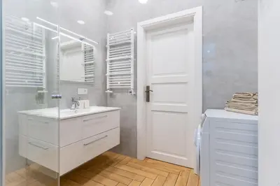 a white bathroom with a sink and a mirror at Picturesque Old Town Apartment with Charming Balcony in Kaunas